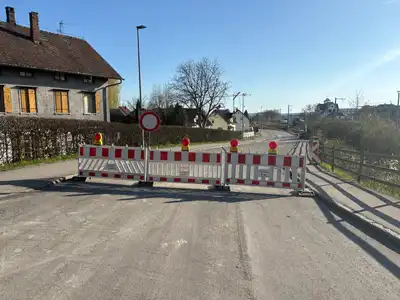 Straßensperrung mit Absperrgittern und Durchfahrtsverbot-Schild blockiert Gemeindestraße bei Wohngebäuden